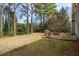 Expansive backyard area featuring mature trees, a stone patio with a grill, and a cozy fire pit at 1390 Bridle Path Dr, Lawrenceville, GA 30045