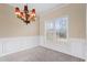 Bright dining room featuring a chandelier, plush carpeting, wainscoting, and a large window at 1390 Bridle Path Dr, Lawrenceville, GA 30045
