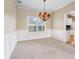Dining room with a large window, plush carpeting, classic wainscoting, and chandelier at 1390 Bridle Path Dr, Lawrenceville, GA 30045