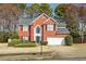 Charming two-story brick home featuring a two-car garage and a well-manicured front yard with mature trees at 1390 Bridle Path Dr, Lawrenceville, GA 30045