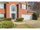 Close up of the front of a brick home with a black door and a two-car garage at 1390 Bridle Path Dr, Lawrenceville, GA 30045