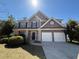 Traditional two-story home featuring a two-car garage and manicured lawn at 2728 Sandalwood Cir, Locust Grove, GA 30248