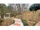 Landscaped backyard with brick path, white benches, and a variety of trees and plants at 679 Victorian Cir, Dallas, GA 30157