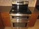 Close-up of stainless steel double oven and cooktop with wood cabinets at 9165 Eves Cir, Roswell, GA 30076