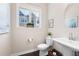 A clean and bright powder room with a pedestal sink, oval mirror, and window with neighborhood view at 710 Hudson Way, Roswell, GA 30076