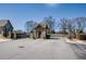 View of the gated community entrance featuring a stone gatehouse, wrought iron fencing, and mature trees at 2300 Hopehaven Way, Hoschton, GA 30548