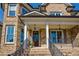 Inviting front porch with stone accents, a wooden door, and classic columns offering curb appeal at 2300 Hopehaven Way, Hoschton, GA 30548