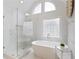 Bright bathroom featuring a modern tub, a glass shower, and decorative tilework by a large window at 3966 Creekview Ridge Dr, Buford, GA 30518
