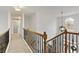 Upstairs hallway with wood and iron banister leads to bedrooms; pendant lighting and window accents at 3966 Creekview Ridge Dr, Buford, GA 30518