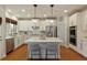 A bright, modern kitchen features white cabinetry, stainless steel appliances, and a marble countertop island with seating at 3966 Creekview Ridge Dr, Buford, GA 30518