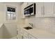 This kitchenette features white cabinets, stainless steel microwave, and a stylish patterned backsplash at 3966 Creekview Ridge Dr, Buford, GA 30518