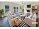 Bright living room with fireplace, two white sofas, large windows, and french doors to outdoor deck at 1200 Platinum Dr, Hoschton, GA 30548