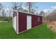 Burgundy outbuilding featuring a roll-up door, entry door, and window, set on a lush green lawn at 555 N Lake N Dr, Covington, GA 30016