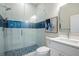 Modern bathroom featuring glass enclosed shower with blue tiled accent and pebble floor, a toilet, and vanity at 916 Ira Sw St, Atlanta, GA 30310