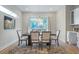 Well-lit dining room with a sleek wooden table, six chairs, modern light fixture, and large backyard-facing window at 916 Ira Sw St, Atlanta, GA 30310