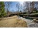 Stone swimming pool and grassy backyard area with manicured landscaping and trees at 3180 Wills Mill Rd, Cumming, GA 30041