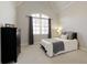 Comfortable bedroom with natural light has neutral carpet, a bed with a grey blanket, and a dark wooden dresser at 3180 Wills Mill Rd, Cumming, GA 30041