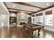 Spacious game room with a pool table, stone fireplace, wood beams, and built-in shelving at 3180 Wills Mill Rd, Cumming, GA 30041