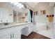 Bright bathroom showcasing double granite vanities, white cabinets, and a tiled soaking tub at 76 Barrington Farms Pkwy, Sharpsburg, GA 30277