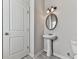 Cozy half bathroom featuring pedestal sink, new vanity light fixture, and wood-look floors at 426 Parkstone Dr, Woodstock, GA 30188