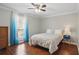 Bedroom with hardwood floors, ceiling fan, bed, bright window with sheer blue curtains, and side tables at 603 Dunbar Dr, Dunwoody, GA 30338