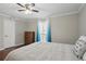 Bedroom featuring hardwood floors, ceiling fan, soft bed, and bright window with sheer blue curtains at 603 Dunbar Dr, Dunwoody, GA 30338