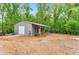 Detached garage with side carport and level gravel driveway in wooded area at 3568 Univeter Rd, Canton, GA 30115