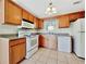 Kitchen with wooden cabinets, white appliances, and tile floors, offering a functional space for cooking at 242 Meadow Spring Dr, Temple, GA 30179