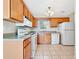 Kitchen with wooden cabinets, white appliances, and tile floors, offering a practical cooking area at 242 Meadow Spring Dr, Temple, GA 30179