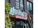 Personal installing a bright, vintage-style 'Junior's Pizza' sign with a directional arrow on a commercial building at 26 Ormond, Atlanta, GA 30315