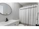 Modern bathroom with a sleek vanity, round mirror, and shower with patterned curtain at 266 Carthage Blvd, Rockmart, GA 30153