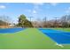 View of community tennis courts featuring a green and blue surface, fencing, and lighting at 795 Saddle Ridge Trce, Roswell, GA 30076