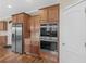 Close-up view of kitchen with stainless steel appliances, wood cabinets, granite counters, and hardwood flooring at 8116 Powhattan Ct, Mcdonough, GA 30252