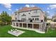 A beautifully landscaped backyard with a stone fire pit area, a deck, mature trees, and lush green grass at 4865 Meadow Park Ln, Suwanee, GA 30024