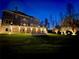 Night shot of the backyard featuring a lit patio, expansive lawn, and manicured landscaping at 4865 Meadow Park Ln, Suwanee, GA 30024