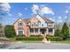 Beautiful brick home with covered front porch and manicured landscaping under a partly cloudy blue sky at 4865 Meadow Park Ln, Suwanee, GA 30024