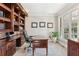 Office with built-in wooden cabinets, desk and natural light from a large window at 4865 Meadow Park Ln, Suwanee, GA 30024