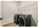 Laundry room with side by side black washer and dryer units with wooden floors and wire shelf at 3114 Thicket Ln, Atlanta, GA 30349