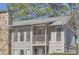 Exterior view highlighting a balcony and stone chimney of a multi-story condo building at 3852 Woodridge Way, Tucker, GA 30084