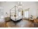 A relaxing bedroom features a four-poster bed, stylish light fixture, neutral color palette, and hardwood floors at 11279 Serenbe Ln, Chattahoochee Hills, GA 30268