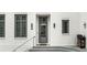 A charming gray front door with transom window and wreath, flanked by two large windows at 11279 Serenbe Ln, Chattahoochee Hills, GA 30268