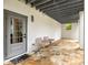 Covered outdoor patio with a stone floor, seating and view to the backyard at 11279 Serenbe Ln, Chattahoochee Hills, GA 30268