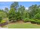 Scenic backyard view, showcasing lush greenery, mature trees, pond, and a glimpse of a wooden bridge at 3286 Sweetleaf Ln, Buford, GA 30519