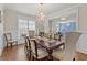 Chandelier illuminates a wood dining table with seating, complemented by wood floors and a sunlit window at 3286 Sweetleaf Ln, Buford, GA 30519