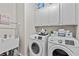 Bright laundry room features modern white appliances, upper cabinets, and a utility sink for added convenience at 3286 Sweetleaf Ln, Buford, GA 30519