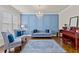 Stylish living room with a blue accent wall, tufted sofa, and a beautiful chandelier, creating an inviting atmosphere at 3286 Sweetleaf Ln, Buford, GA 30519