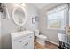 Well-lit bathroom with a white vanity, toilet, and decorative mirror at 239 Sumac Trl, Woodstock, GA 30188