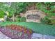 Landscaped entrance to Woodlands community featuring a stone sign surrounded by lush greenery and colorful flowers at 239 Sumac Trl, Woodstock, GA 30188