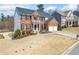 Beautiful two-story brick home with two-car garage, black shutters and small front yard garden bench at 239 Sumac Trl, Woodstock, GA 30188