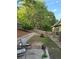 Spacious backyard with mature trees, lawnmower, and retaining wall at 60 Saddle Tree Way, Sugar Hill, GA 30518